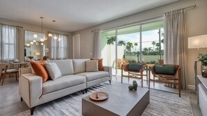 A modern living room with a sofa, coffee table, and chairs. There is a dining area with a table and chairs, and a large window with a view of palm trees. - Luxury Villa With Private Pool Close to Disney (Kissimmee)