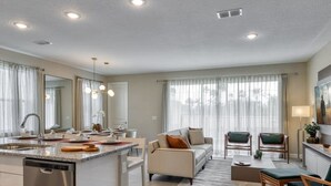 A modern kitchen with a dishwasher, a dining area with a table and chairs, a sofa, and a TV. - Luxury Villa With Private Pool Close to Disney (Kissimmee)