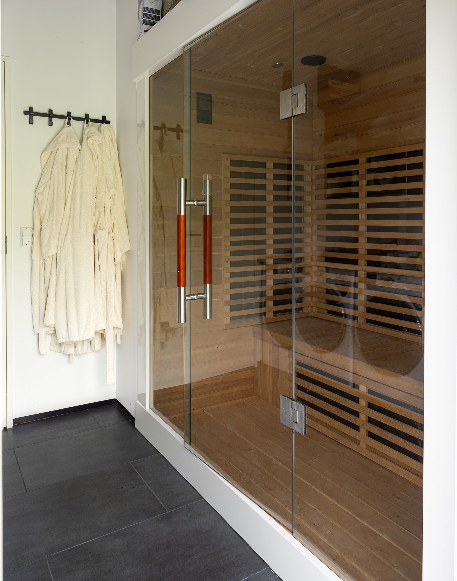 Une salle de bain moderne avec une douche à parois de verre, un plancher en bois et un porte-serviettes fixé au mur.