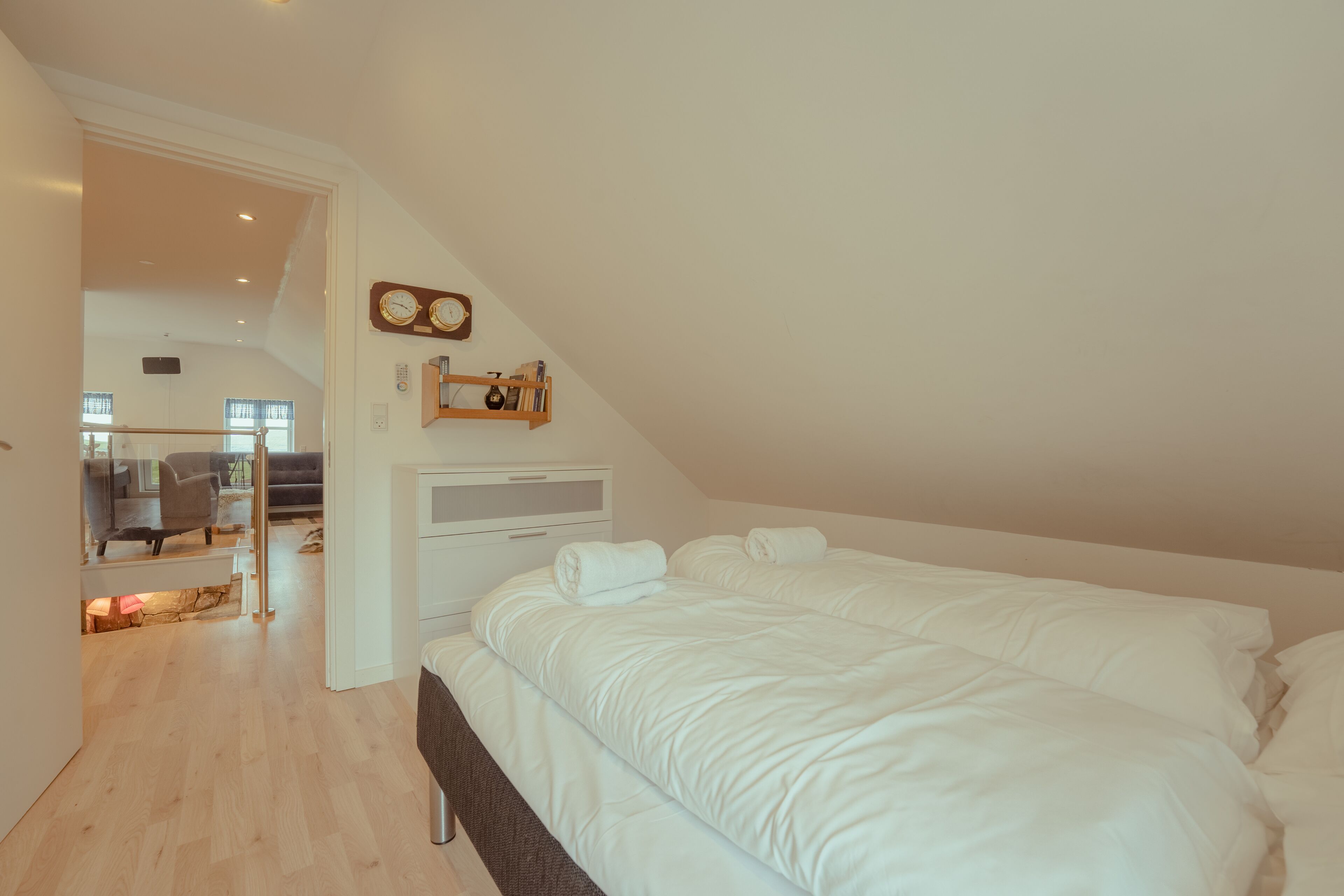 A modern bedroom with a large bed, a bedside table, and a wall-mounted clock.