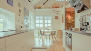 Een moderne keuken met een centraal kookeiland, een eetgedeelte met uitzicht en een accentmuur van steen.