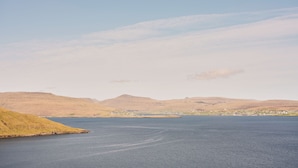 A calm lake with a small island and distant hills. - Studio Apartment | Unique Location | Stunning View (Hoyvík)