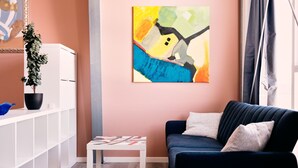 A modern living room with a dark blue sofa, a white coffee table, and abstract paintings on the wall. - Studio Apartment | Unique Location | Stunning View (Hoyvík)