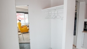 A room with a tiled floor, a wooden ceiling, and a white wall with a hanging clothes rack. - Hyggeligt | Nordens Hus | Bager | Svartifossur (Tórshavn)