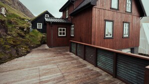 Et træhus med skråtag, en træterrasse og udsigt til en skråning.