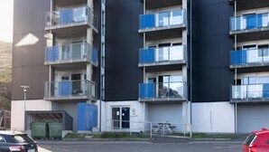 A modern multi-story building with balconies, a parking lot, and a clear sky. - Stunning Sea View | 1 Bedroom Apartment | Tórshavn (Tórshavn)