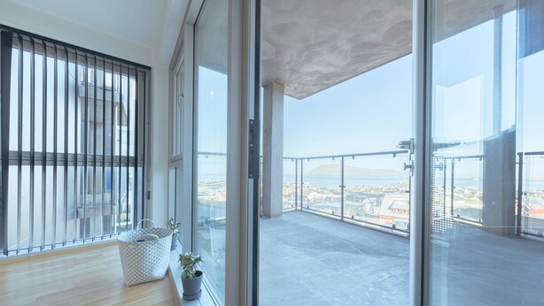 A spacious balcony with a city view, a wooden floor, and a potted plant. - Stunning Sea View | 1 Bedroom Apartment | Tórshavn (Tórshavn)