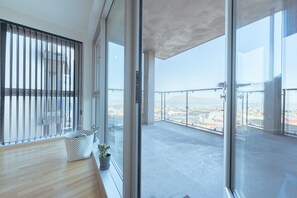 A spacious balcony with a city view, a wooden floor, and a potted plant. - Stunning Sea View | 1 Bedroom Apartment | Tórshavn (Tórshavn)