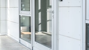 A modern building entrance with glass doors, a metal handle, and a doormat. - Stunning Sea View | 1 Bedroom Apartment | Tórshavn (Tórshavn)