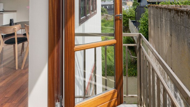 A wooden-framed glass door leading to a balcony with a view of a residential area. - Marina View |3 Bedroom Apartment |Central Tórshavn (Tórshavn)