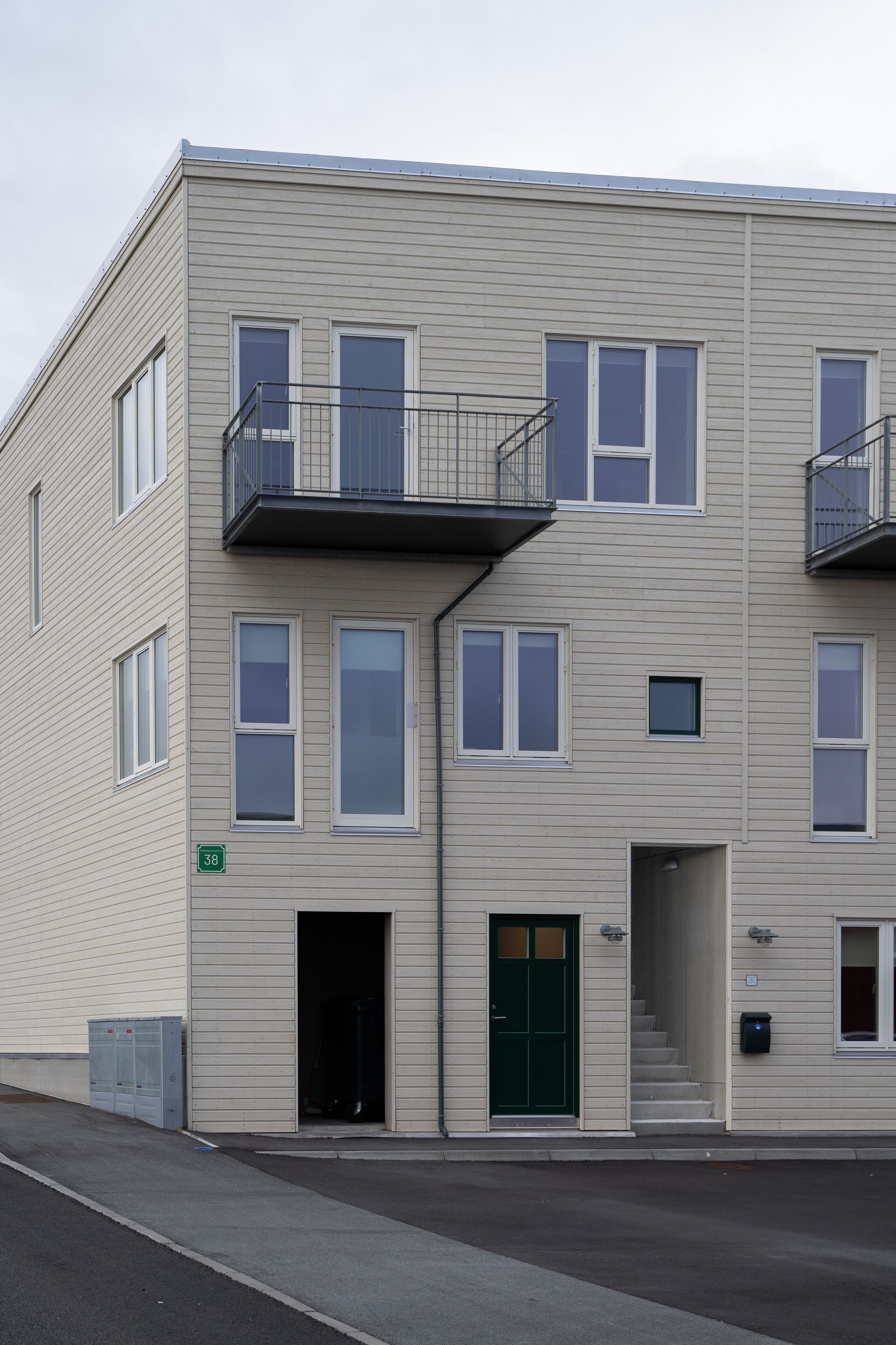 A multi-story building with a flat facade, balconies, and a green door.