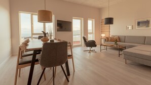 Amplia sala de estar con una mesa de comedor, sillas, un sofá y un televisor montado en la pared.