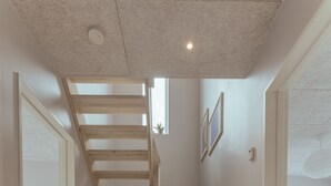 Un interior moderno con una escalera de madera que sube a un dormitorio tipo loft.