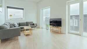 Un salon moderne avec un canapé gris, une table basse en bois et un téléviseur.