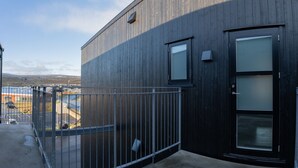 Een gebouw met een donker houten gevel, een metalen hekwerk en een deur met geëtste glaspanelen.