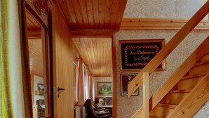 A wooden staircase leading to a dining area with a patterned rug and a framed sign on the wall. - Charming 3 Br Home | Scenic Village | Nature (Eiði)