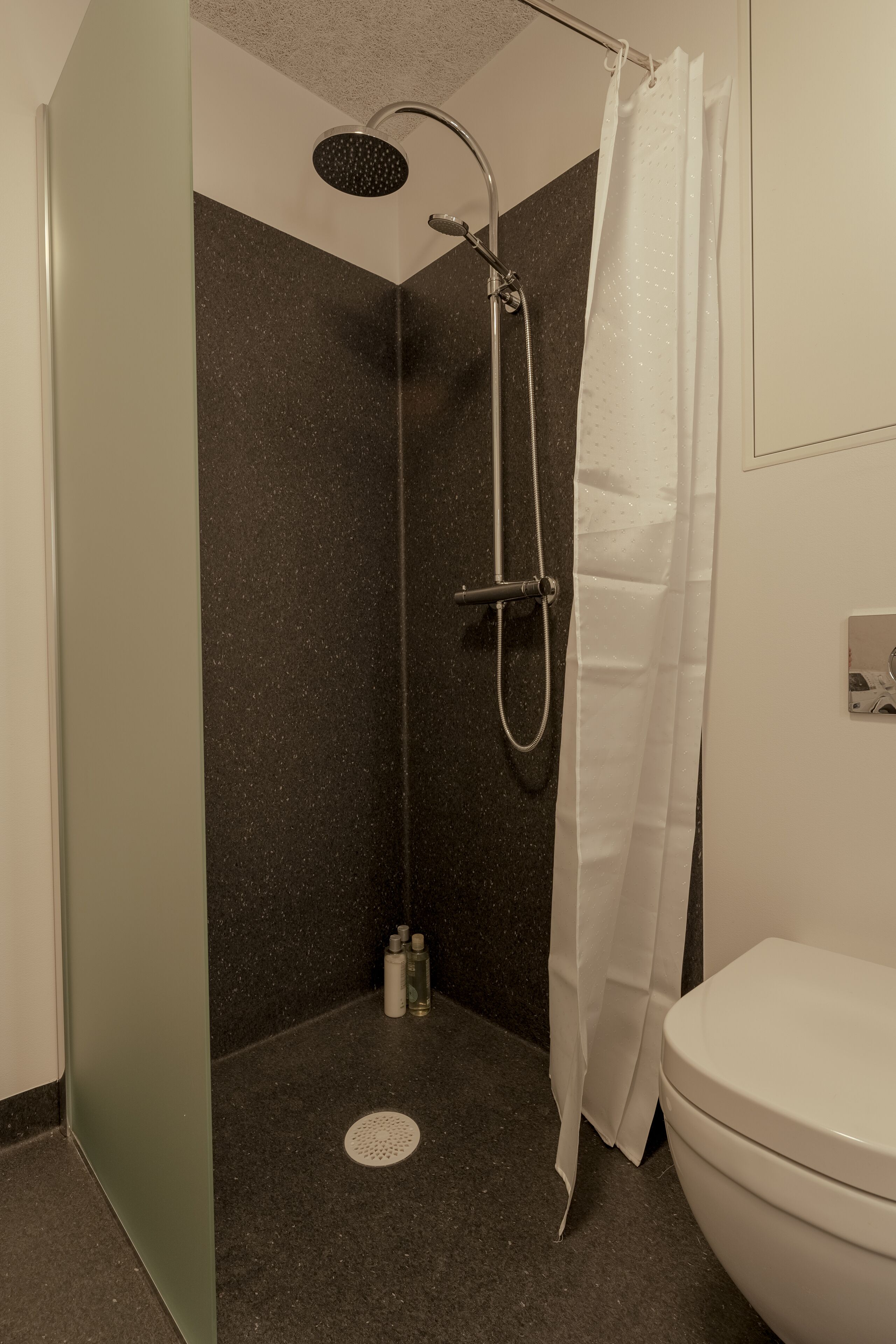 A shower with a handheld showerhead and a curtain.