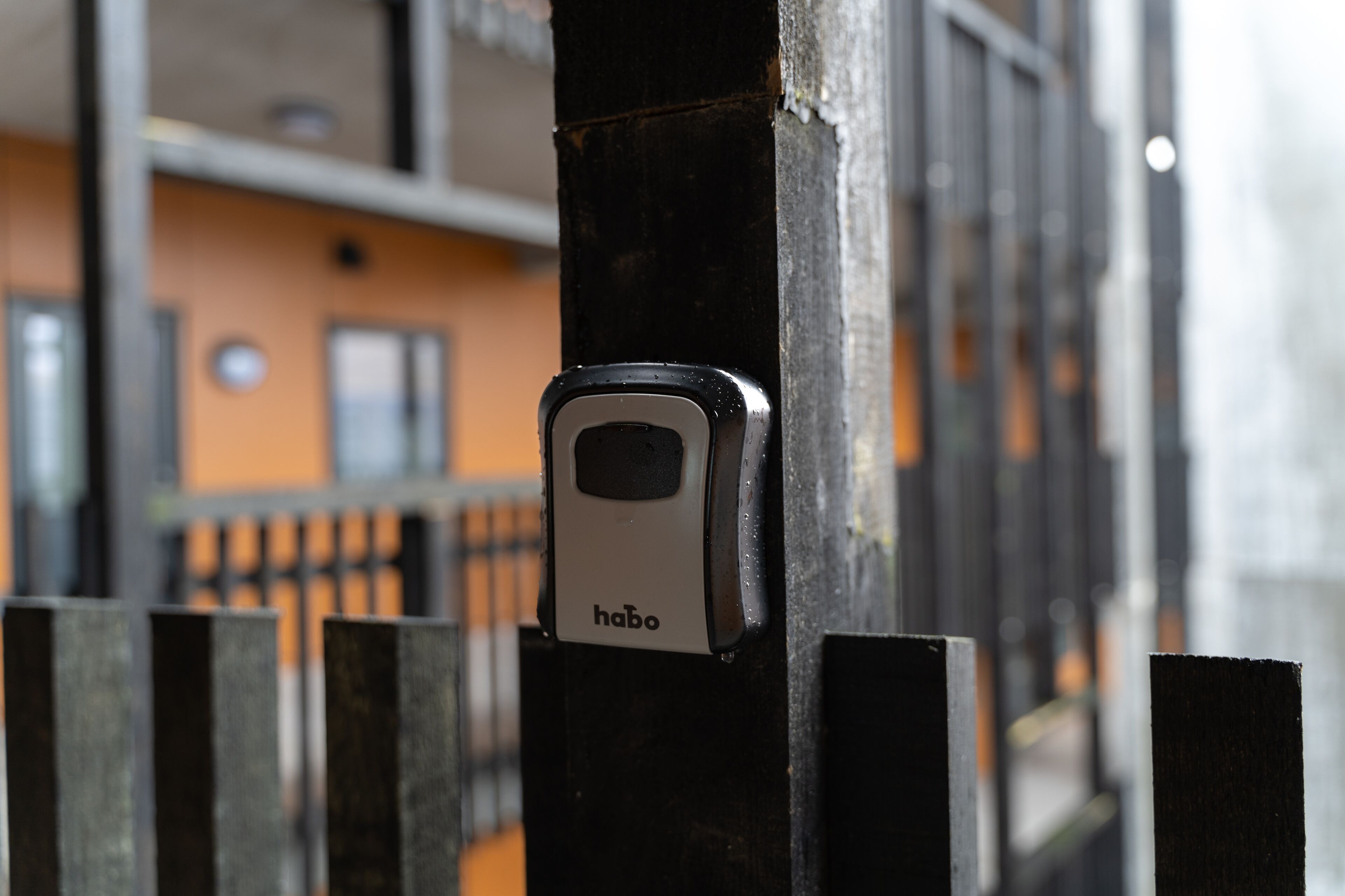 A security lock on a metal gate, with a building in the background.