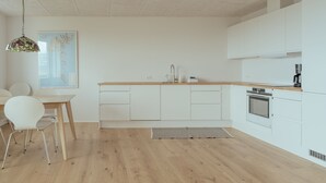 A modern kitchen with white cabinets, a wooden countertop, and a stainless steel oven. - New 2Br Apartment | Sea View (Tórshavn)