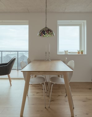 Enjoy meals in this stylish dining area with a large table and pendant light, offering a serene view of the outdoors.