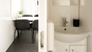 A modern bathroom with a white sink, a mirror, and a black trash can. - Cozy Container Rental | 3Br | 20 Min To Capital (Strendur)