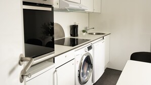 A compact kitchen with a built-in oven, a coffee maker, a sink, and a washing machine. - Cozy Container Rental | 3Br | 20 Min To Capital (Strendur)