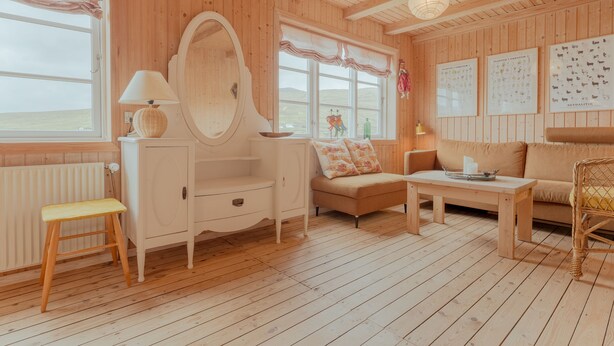 Un interior de madera con un sofá, una mesa, una silla, un espejo y una ventana con vistas.