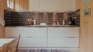 Una cocina moderna con armarios blancos, baldosas negras y paredes de madera.