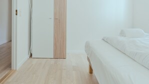 A bedroom with a bed, a wardrobe, and a wooden floor. - 1 Bedroom Apartment | Central | Tórshavn (Tórshavn)