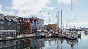 A marina with boats docked, a waterfront promenade, and colorful buildings along the shore. - 1 Bedroom Apartment | Central | Tórshavn (Tórshavn)