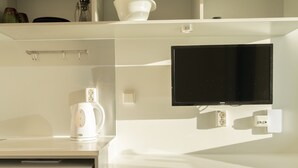 A compact kitchenette with a microwave, kettle, and a flat-screen TV mounted on the wall. - Stylish Studio Apartments (Tórshavn)