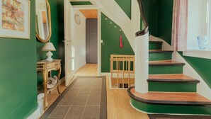 A staircase with green walls and wooden steps, leading to a room with a door and a mirror. - Lovely 4-Br House | Sea View | Nature (Oyndarfjørður)