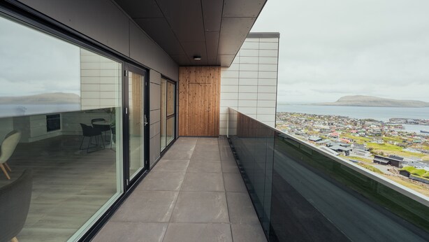 A modern interior with a long corridor leading to a balcony with a city view. - Nordic Swan Aparthotel | Seaview| Stunning 2Br Apt (Tórshavn)