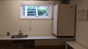 A compact kitchen with a window, sink, and a white refrigerator. - 1 Br Apt | Selatrað | Free Parking (Selatrað)