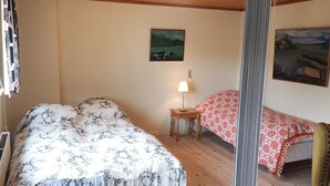 A bedroom with a bed, a nightstand, a lamp, and two paintings on the wall. - 1 Br Apt | Selatrað | Free Parking (Selatrað)