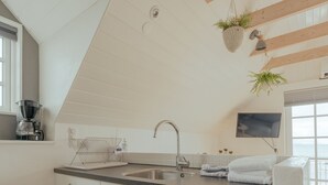 Una cocina moderna con techo de madera, pileta integrada y ventana con vista al mar.