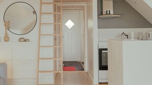 Un loft moderno con techo de madera, una cocina con armarios blancos y un comedor con mesa redonda y plantas.