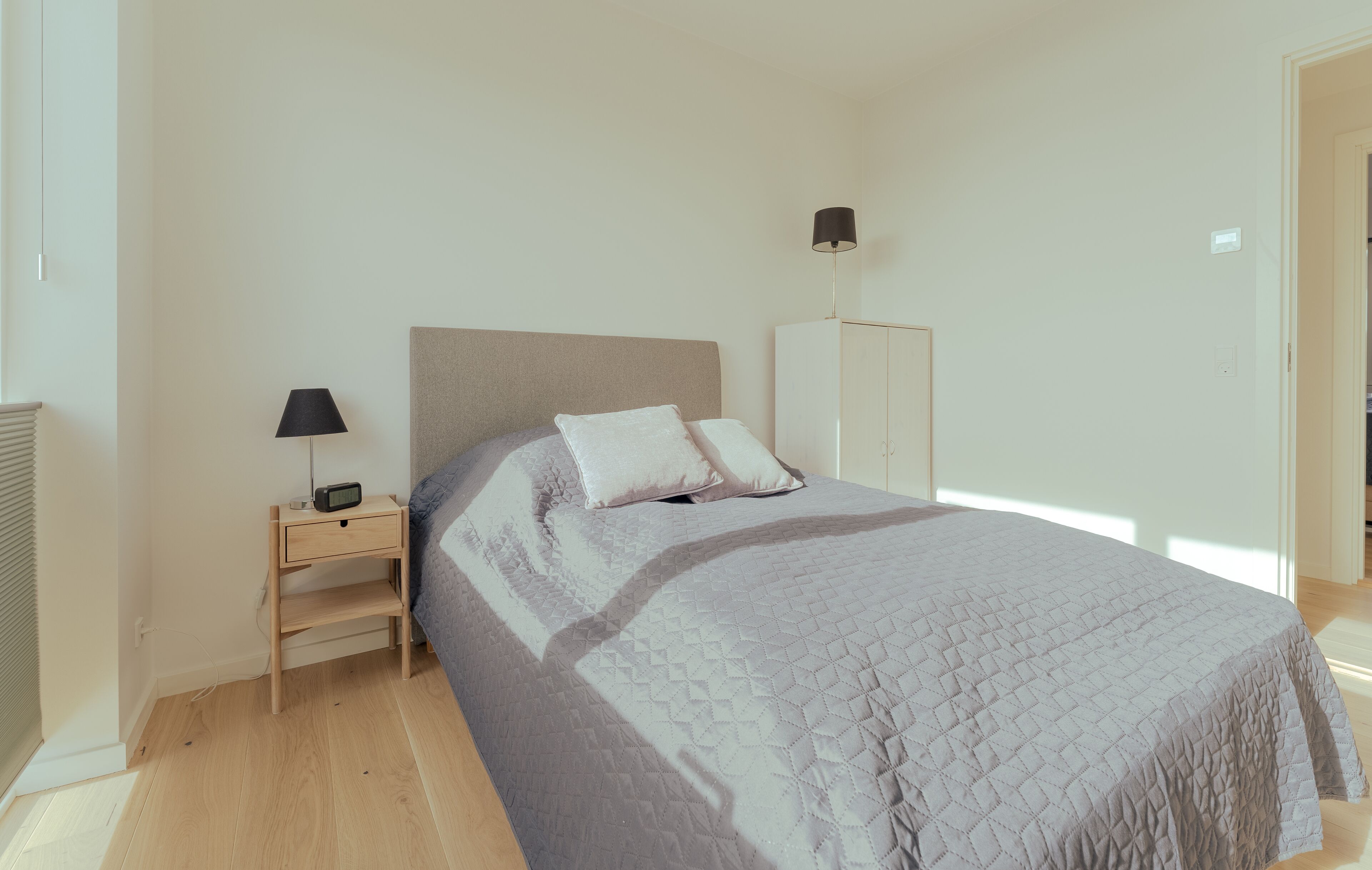 Una camera da letto con un letto, un comodino, una lampada e un armadio.