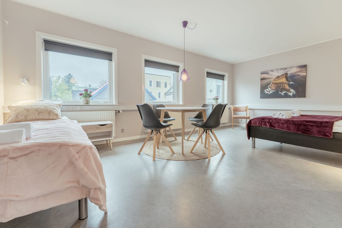 Un dormitorio moderno con cama, mesita de noche y escritorio con sillas.