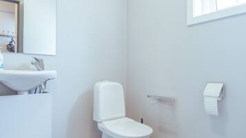 Une salle de bain avec un lavabo blanc, des toilettes et un porte-serviettes.