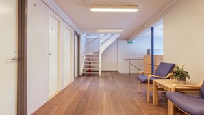 Un pasillo con suelo de madera, una escalera y un área de descanso con sillas y una mesa.