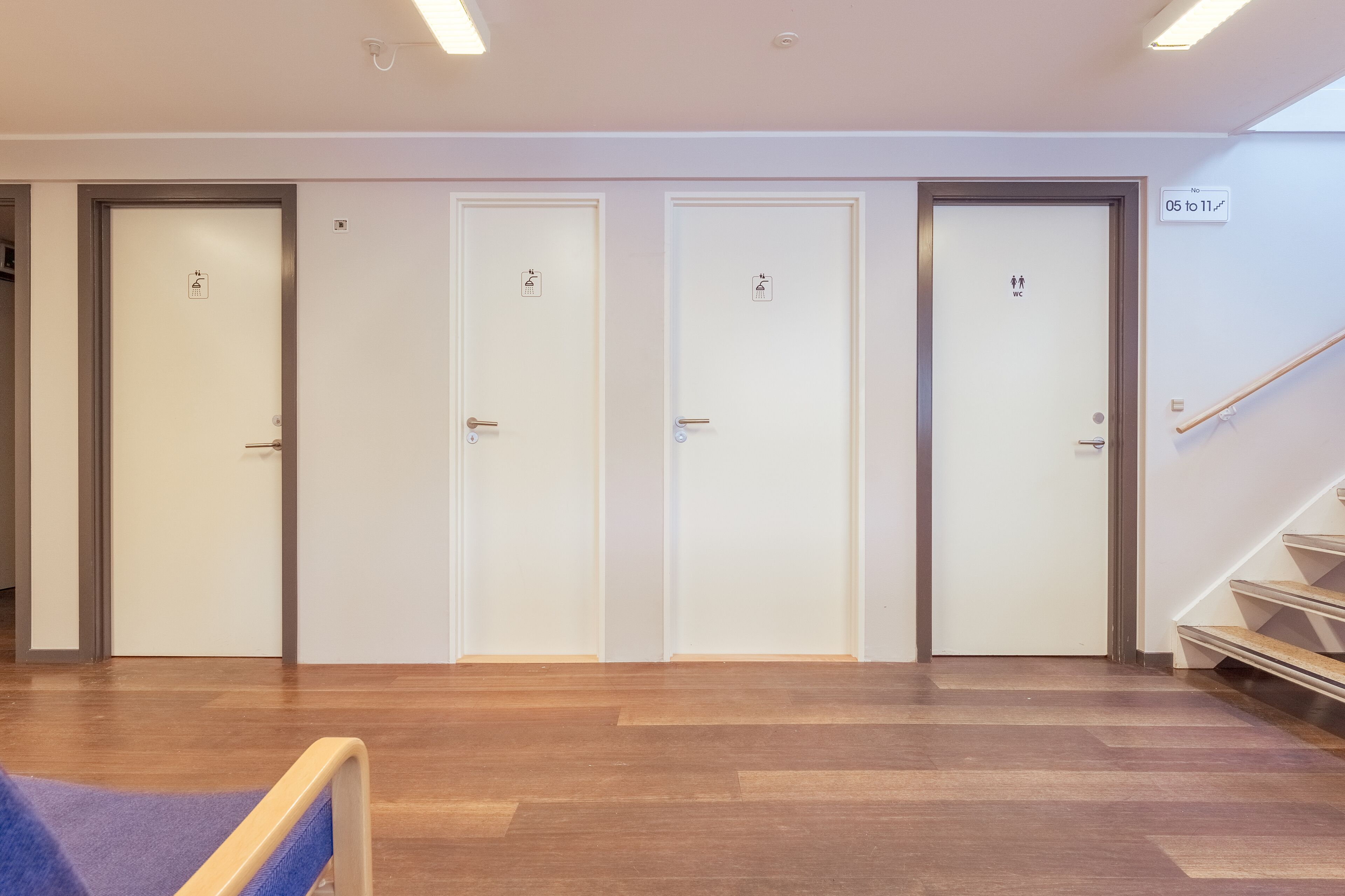 A hallway with four doors, each marked with different symbols indicating facilities. A staircase is visible to the right.