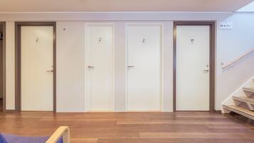 A hallway with four doors, each marked with different symbols indicating facilities. A staircase is visible to the right.