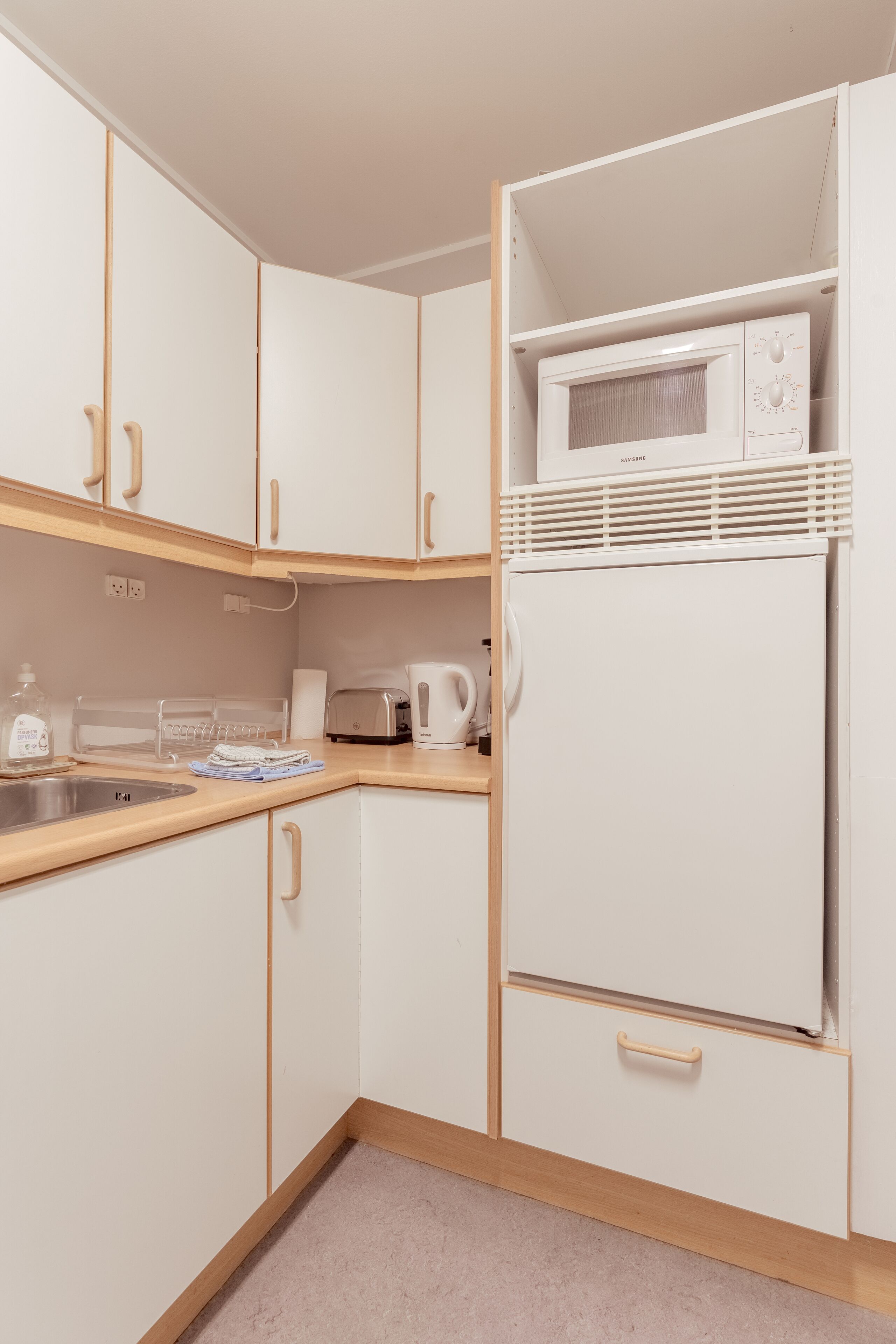 A kitchen with white cabinets, a microwave, a toaster, and a sink.