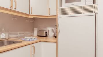 A kitchen with white cabinets, a microwave, a toaster, and a sink.