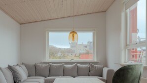 Moderni olohuone, jossa on kulmasohva, puinen sohvapöytä ja vihreä nojatuoli.