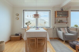 Ein Essbereich mit einem Tisch für vier Personen, einer Couch und einem Fenster mit Blick auf Berge.
