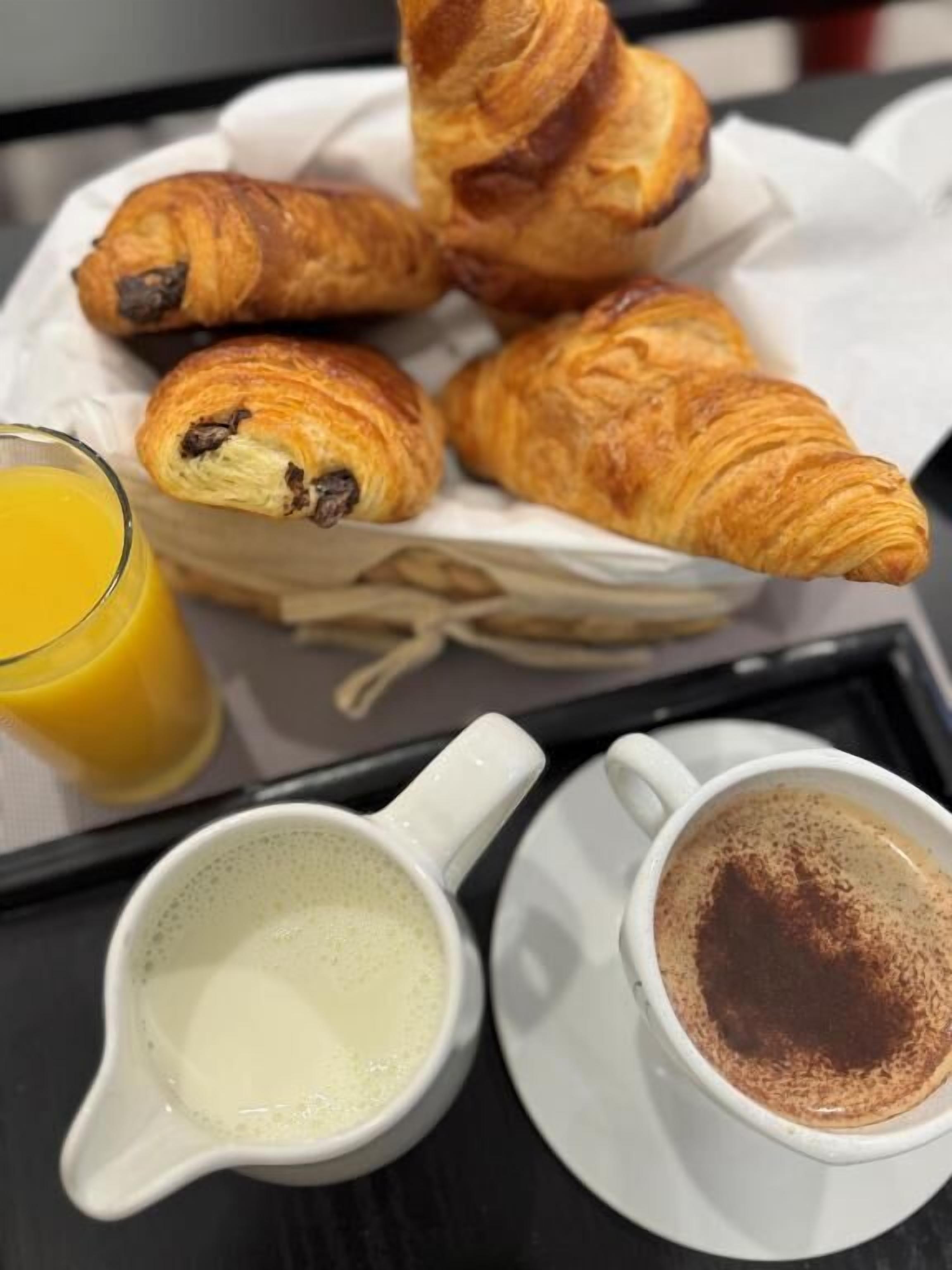 A tray with croissants, a glass of orange juice, and two cups of coffee.