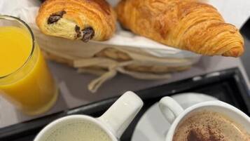 A tray with croissants, a glass of orange juice, and two cups of coffee.