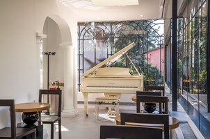Un piano de cola en una habitación luminosa con ventanas grandes, una mesa de comedor y sillas.